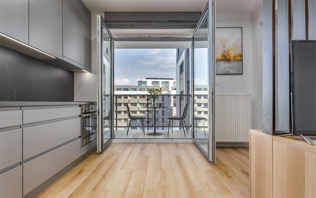 salon, szara zabudowa, czarny blat, drewniana podloga, balkon